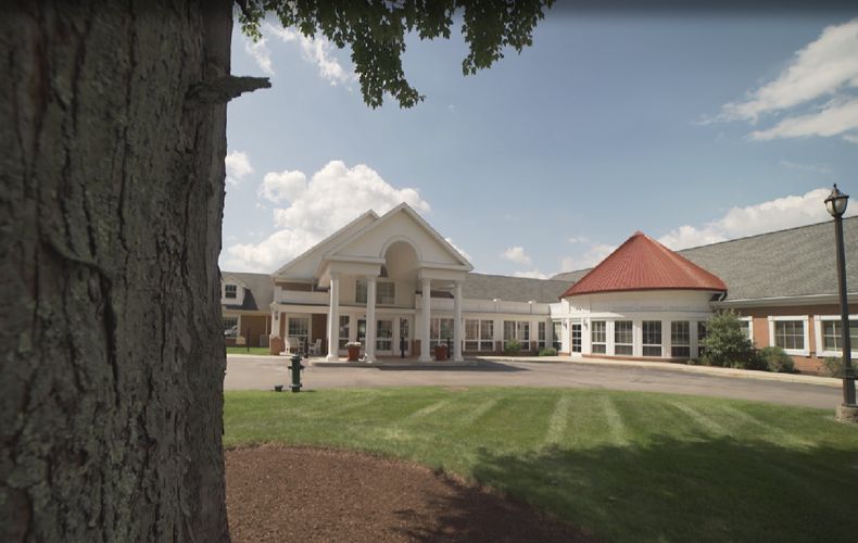 A scenic view of a large resort building with a well-maintained lawn and partly cloudy sky.