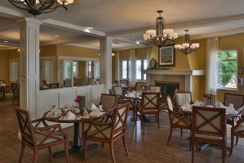 An elegantly designed restaurant dining area with neatly arranged tables and chairs, adorned with chandeliers and a cozy fireplace.