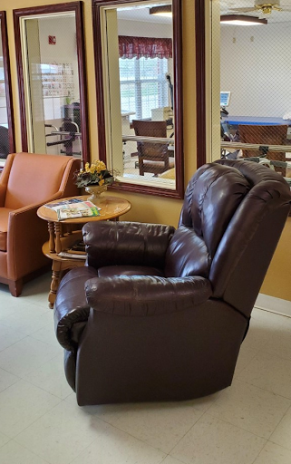 A cozy living room setup featuring a recliner and an orange chair with a small wooden table.