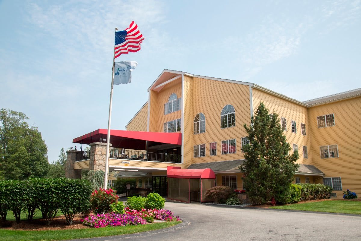 A welcoming hotel entrance with landscaped gardens and flags flying.