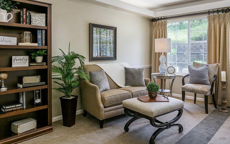 A cozy living room with elegant furnishings, featuring a sofa, a coffee table, and decorative plants.
