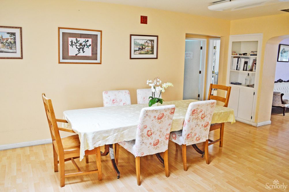 A bright dining room featuring a large table with floral-patterned chairs and wall art.