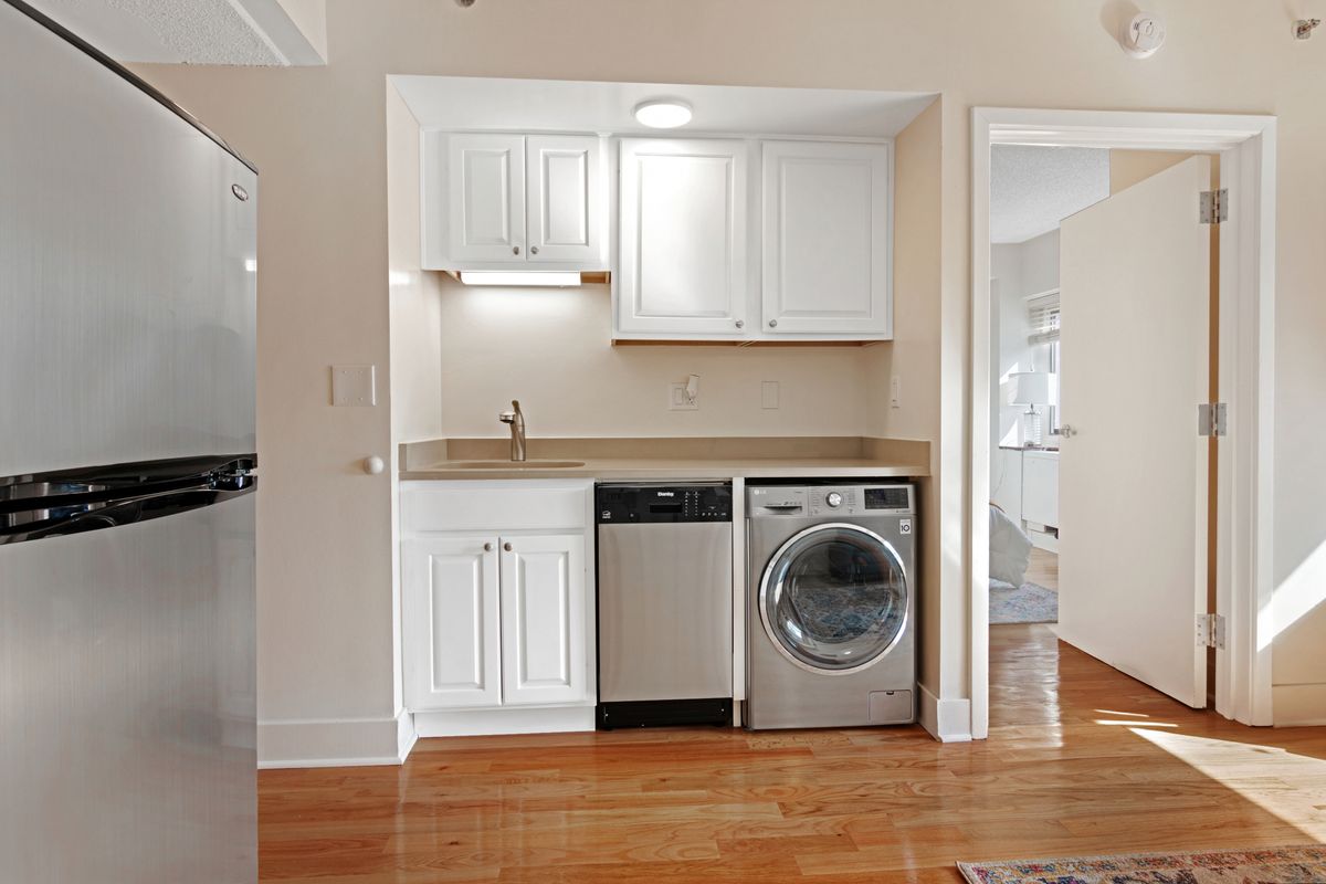 A compact kitchen area with white cabinets, a countertop, and built-in appliances.