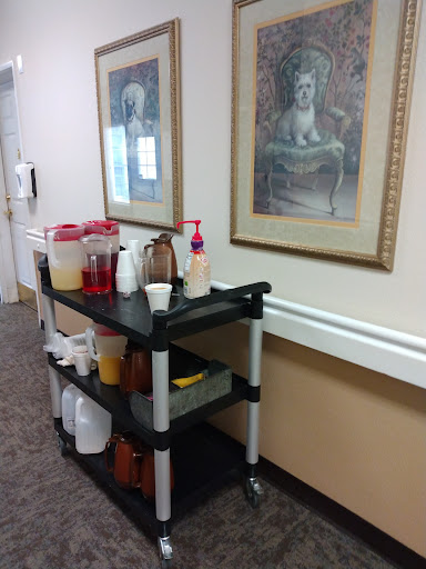 A beverage cart placed in a hallway, featuring various drinks and decorative artwork on the walls.