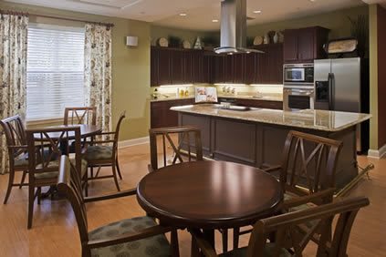 A modern kitchen with an adjacent dining area, featuring dark cabinets and a central table with chairs.