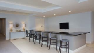 A sleek and minimalist modern bar area with high stools and a flat screen TV.