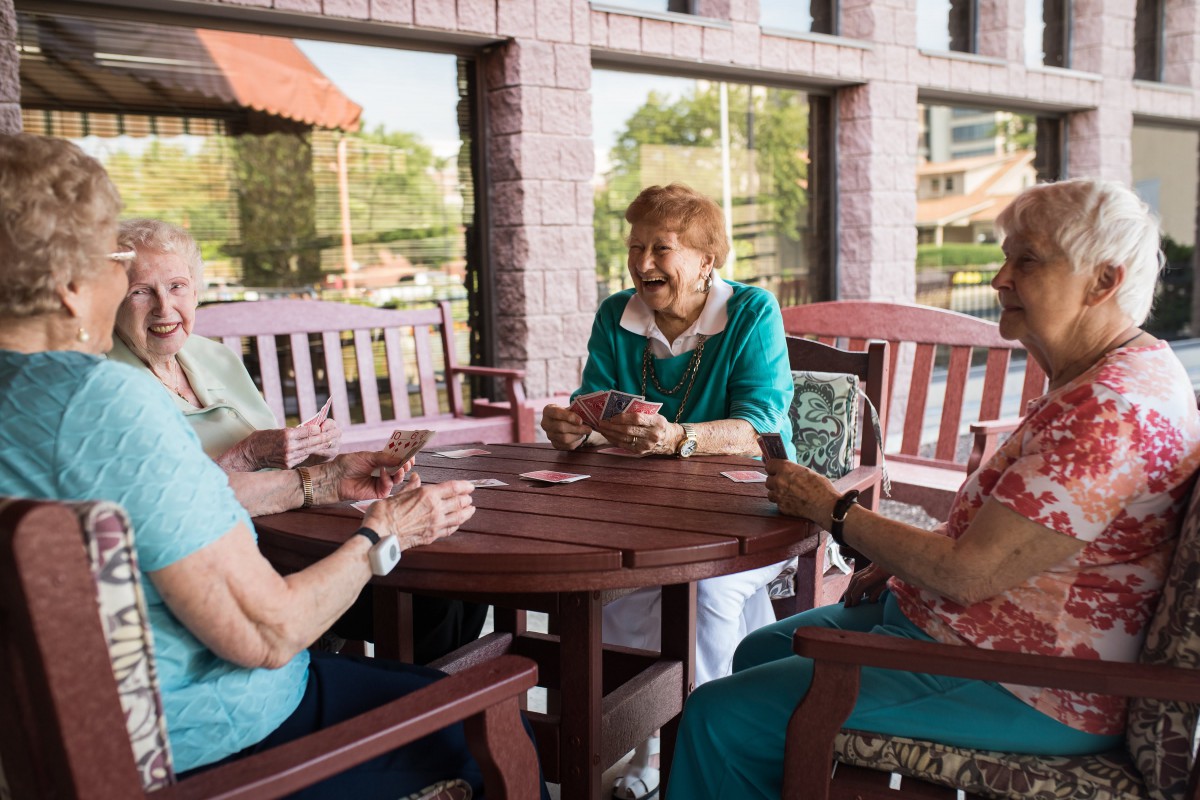 A group of elderly women enjoying a card game together at an outdoor table.