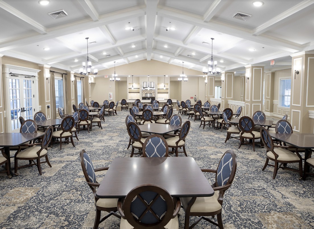 A spacious and elegantly designed dining room with multiple tables and chairs arranged in a symmetrical pattern.