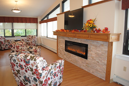A cozy living room featuring a stylish fireplace, floral-patterned chairs, and autumn decorations.