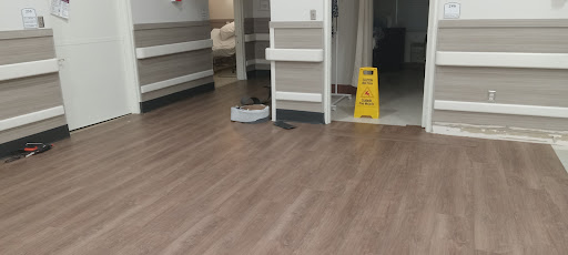 A view of a hospital corridor with a caution sign indicating wet floors and a cleaning device.