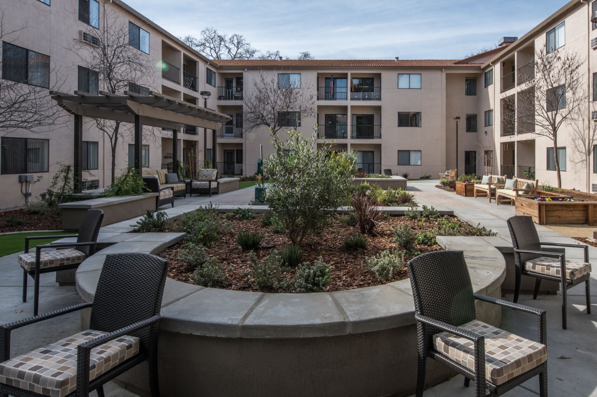 A modern apartment courtyard featuring outdoor seating and well-maintained landscaping.