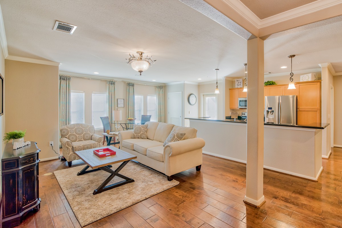 A cozy living room with a comfortable sofa and coffee table, leading into an open kitchen area.
