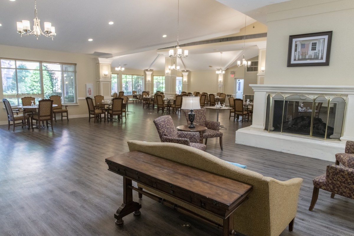 A spacious living and dining area featuring a cozy fireplace, elegant furniture, and a wooden floor.