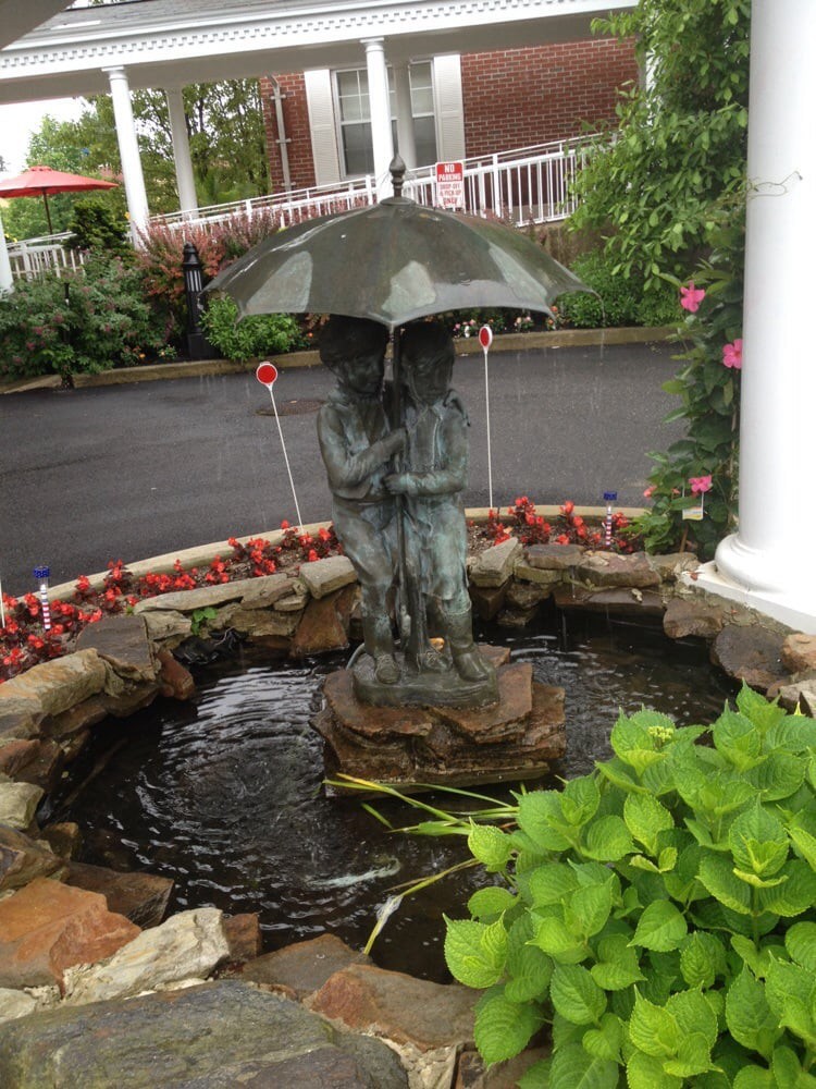 A charming garden statue fountain with a child holding an umbrella.
