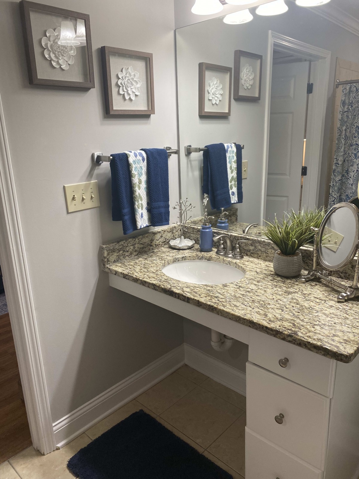 A well-organized bathroom with a granite countertop and blue towels.