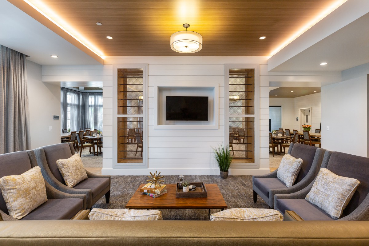 A modern living room with cozy seating and elegant decor, featuring a TV mounted on the wall and warm wooden accents.