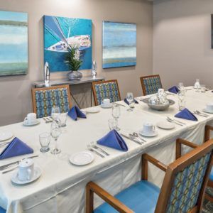 A well-decorated dining room with a neatly arranged table, featuring blue napkins and artwork on the walls.