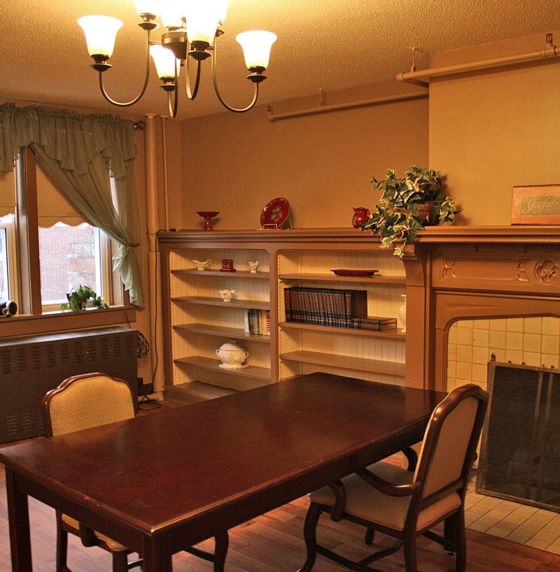 A cozy dining room with a wooden table, chairs, and a fireplace surrounded by bookshelves.