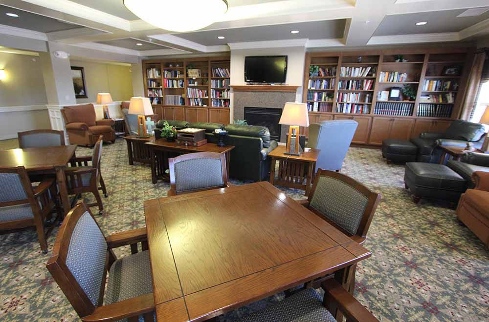 A cozy library reading room with bookshelves, tables, and comfortable seating.