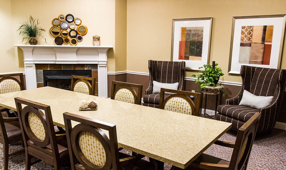 A meeting room with a long table, chairs, artwork on the wall, and a decorative plant.