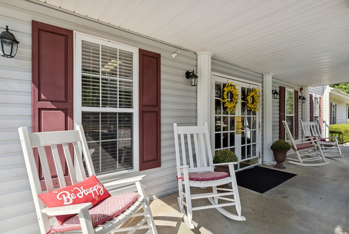A cozy porch with white rocking chairs and decorative wreaths on the door.