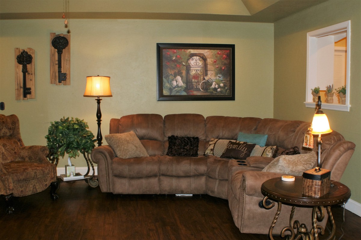 A cozy living room with a sectional couch, floor lamp, and framed painting on the wall.
