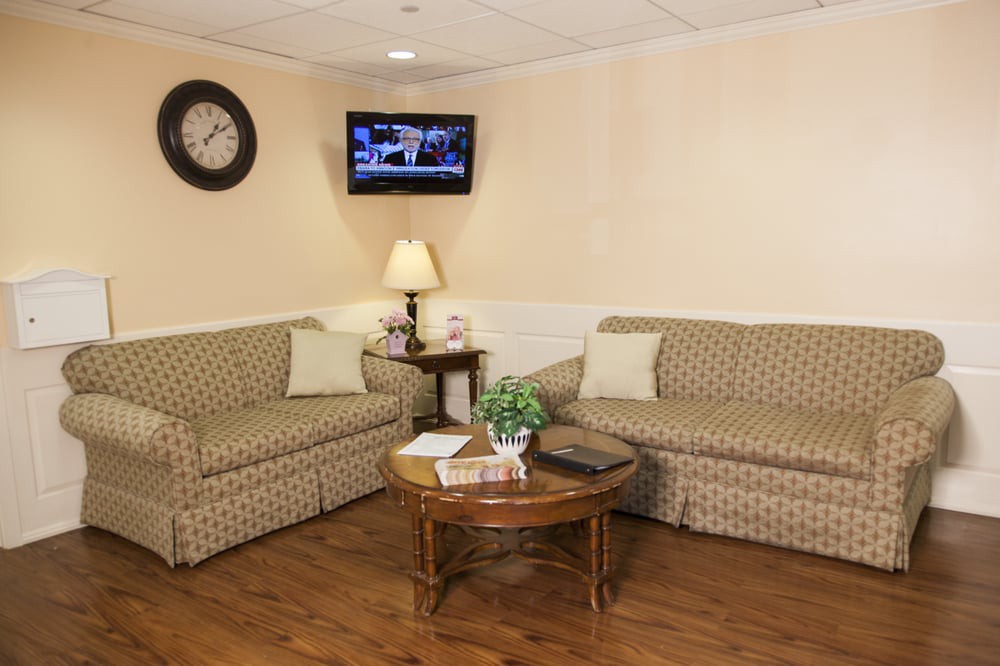 A cozy waiting room with two patterned sofas, a television, and a coffee table.