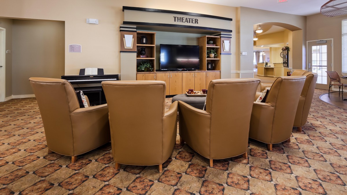 A cozy theater room with leather seating facing a large television.