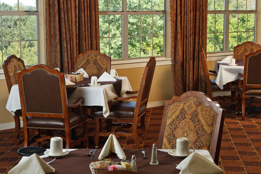 An elegant dining room with neatly set tables and large windows.