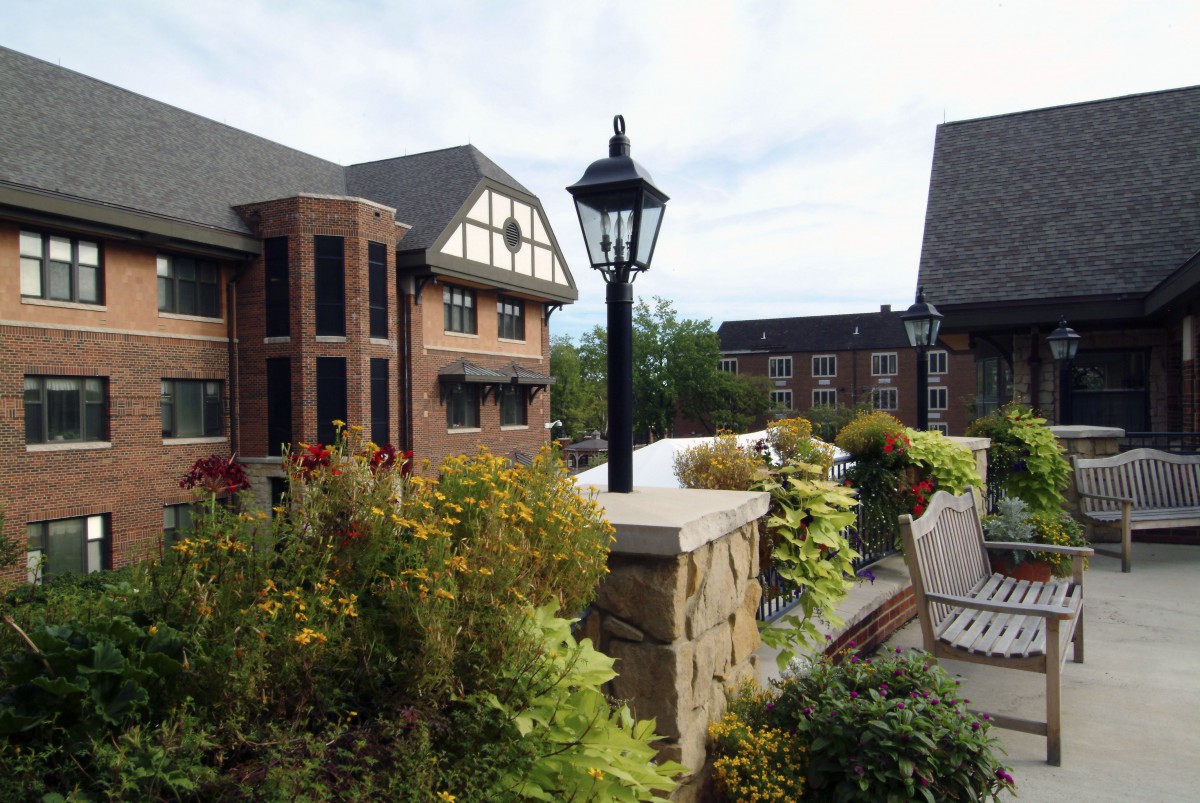 A scenic view of a garden with benches and a traditional-style building in the background.
