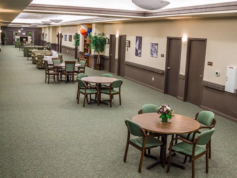 A spacious indoor dining area with multiple tables and chairs, decorated with plants and artwork.