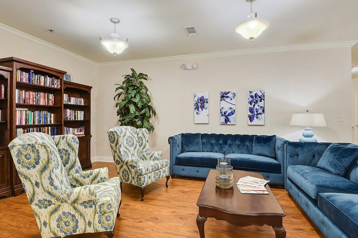 A cozy living room with elegant blue sofas, patterned armchairs, and a wooden coffee table.
