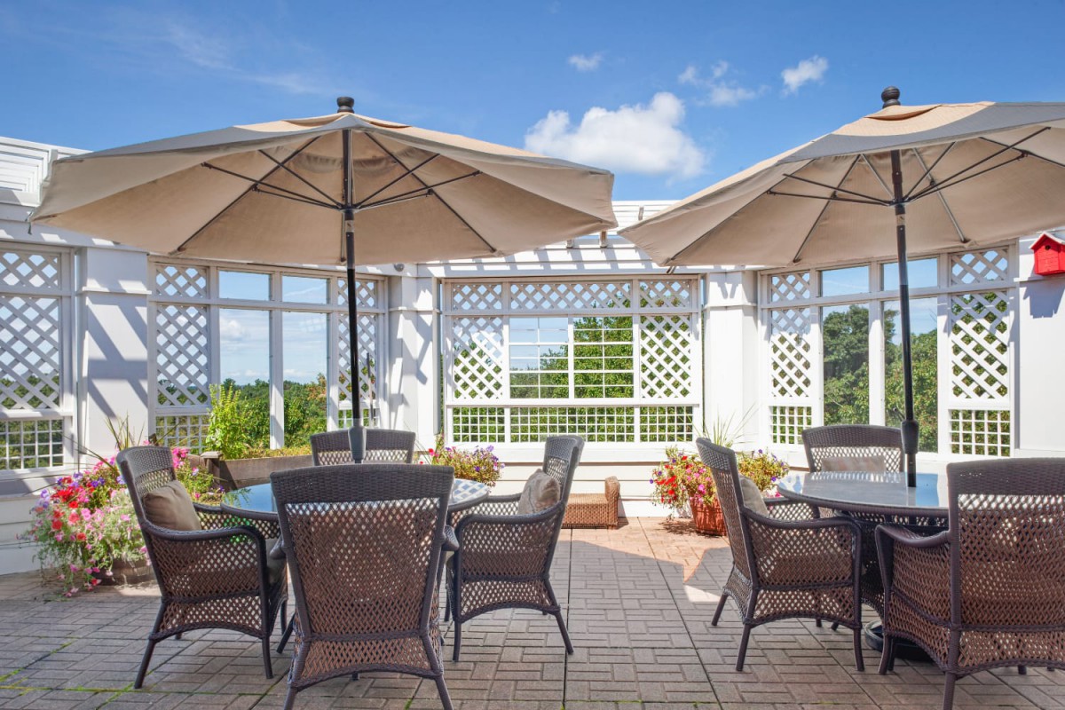 A sunny patio with tables and chairs under large umbrellas.