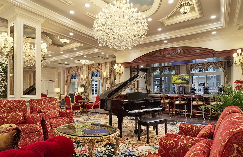 A luxurious hotel lobby featuring a grand piano and an ornate chandelier.