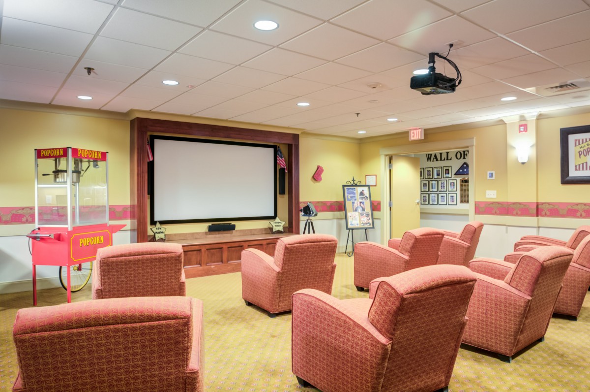A cozy home theater setup with comfortable chairs facing a large projection screen.