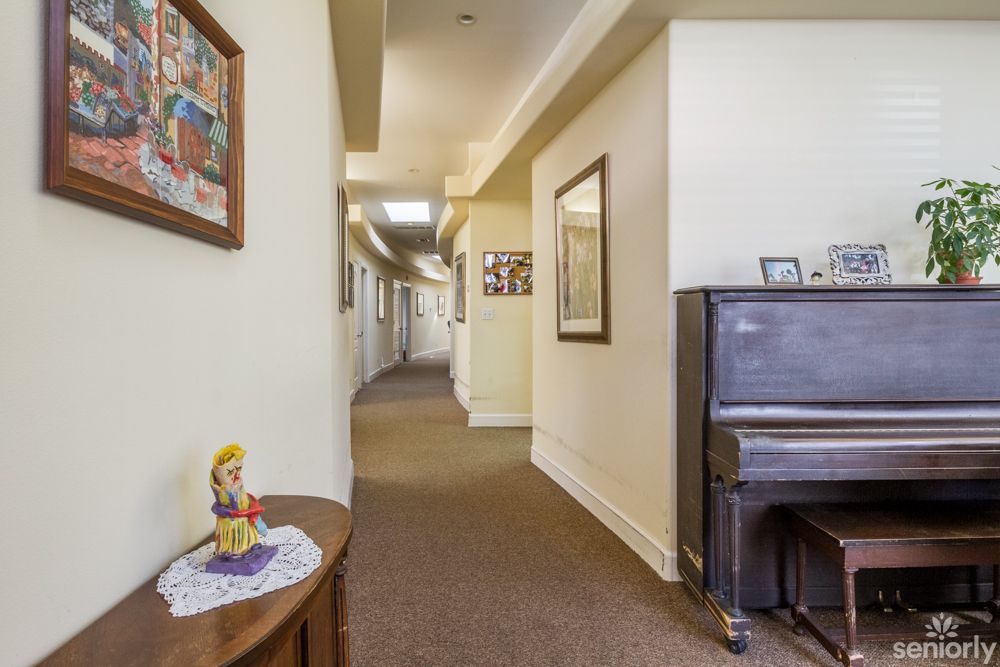 A hallway with a piano and framed wall art.
