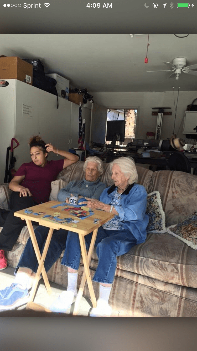 Three people relaxing and playing cards indoors on a sofa.