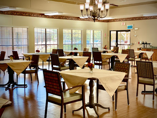 A spacious and well-lit dining area featuring elegantly set tables and comfortable chairs.
