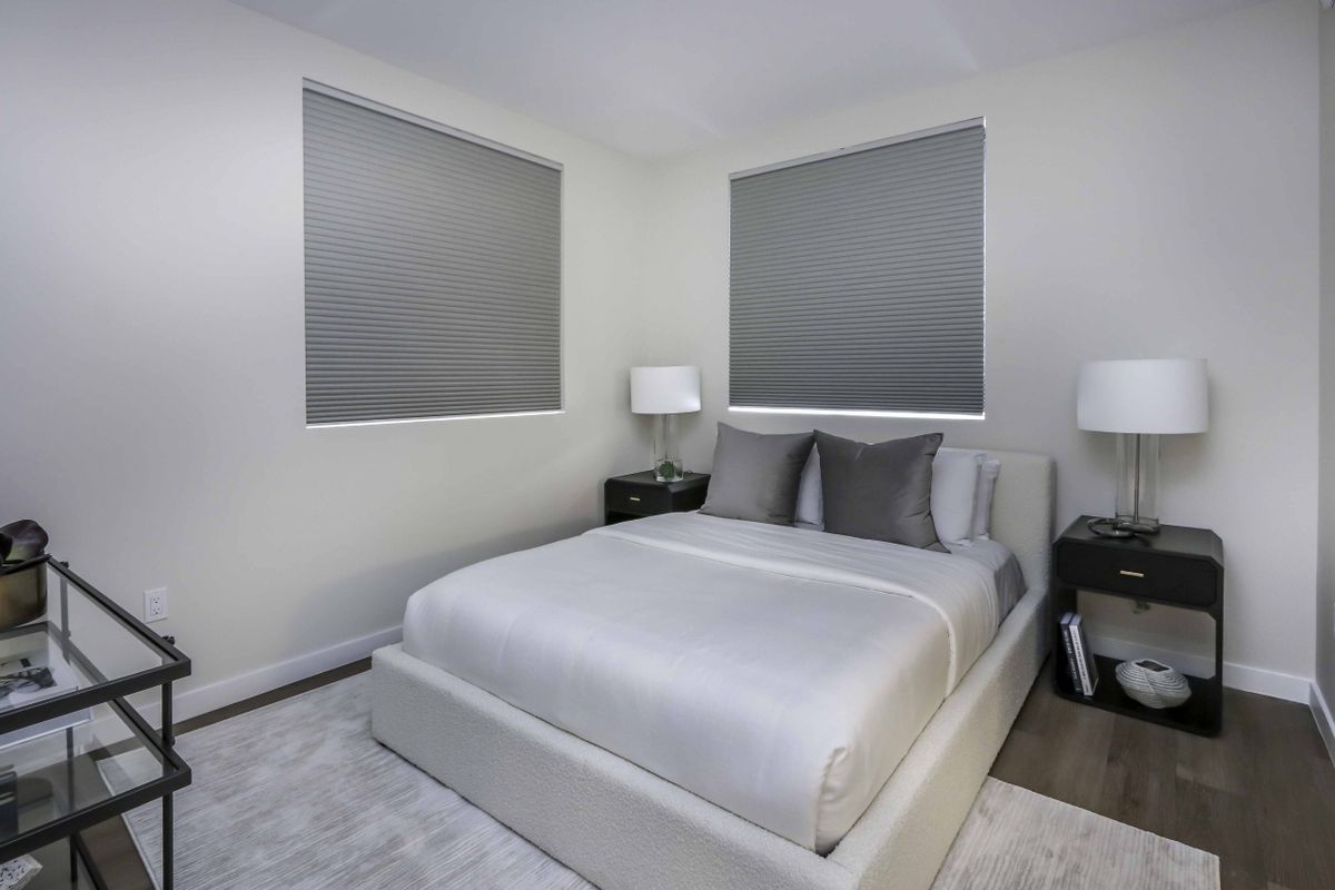 A modern minimalist bedroom with neutral tones and simple furnishings.