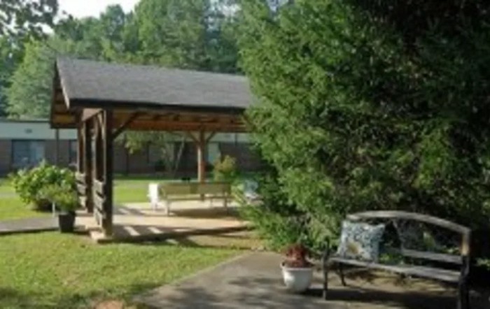 A peaceful garden setting with a gazebo, benches, and greenery.
