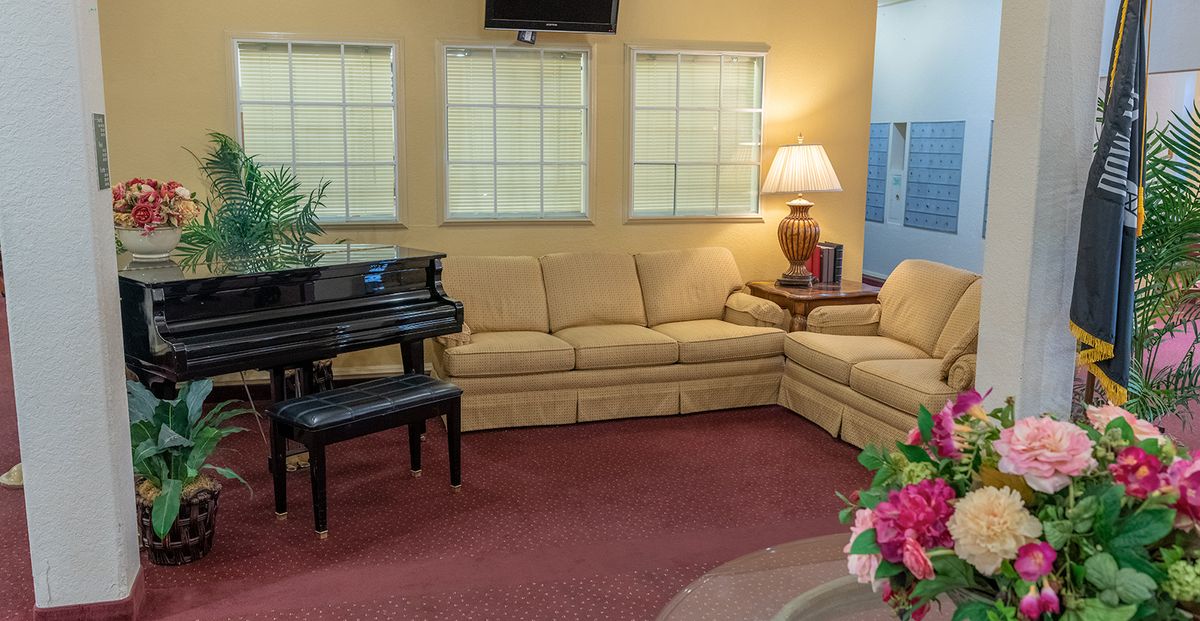 A cozy living room with a large sectional sofa, a piano, and soft lighting.