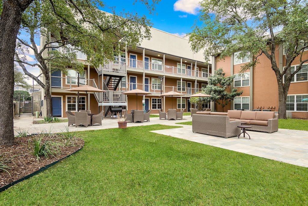 A modern apartment complex with outdoor seating and well-maintained landscaping.