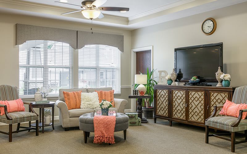A cozy and modern living room with a stylish sofa, leather ottoman, and elegant decor.