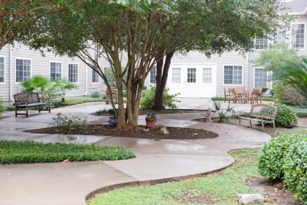 A peaceful courtyard featuring a central tree, winding pathways, and surrounding benches.