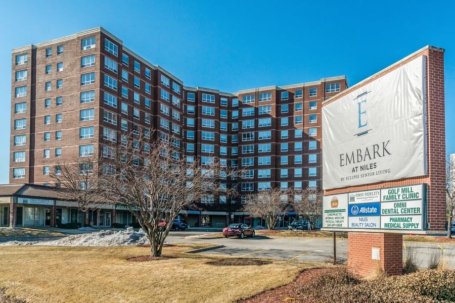 A large hotel building with a prominent sign in front, set against a clear blue sky.
