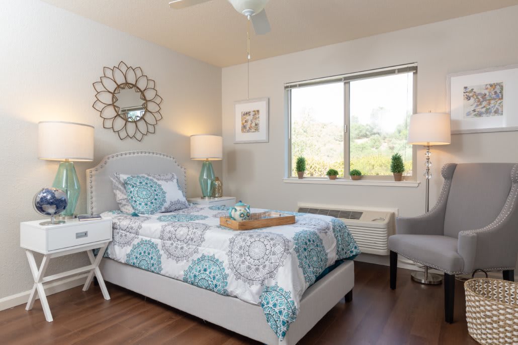 A modern bedroom with stylish decor including a bed with patterned bedding, decorative lamps, and a wall mirror.