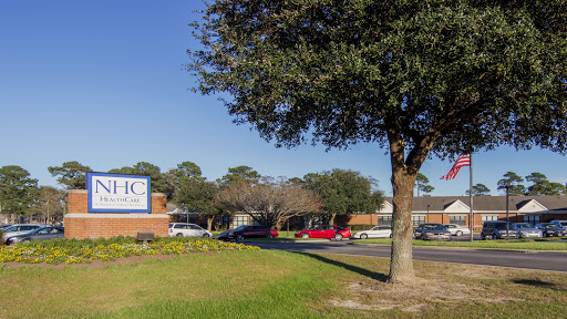 A view of a building with signage, surrounded by greenery and trees under a clear blue sky.