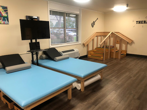 A cozy room equipped with blue mattresses, a television setup, and wooden stairs.
