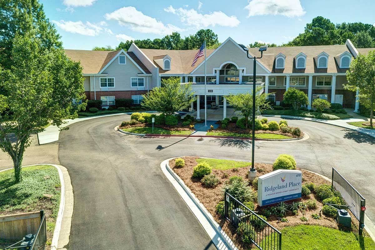 A scenic view of a residential building with a landscaped driveway and greenery.