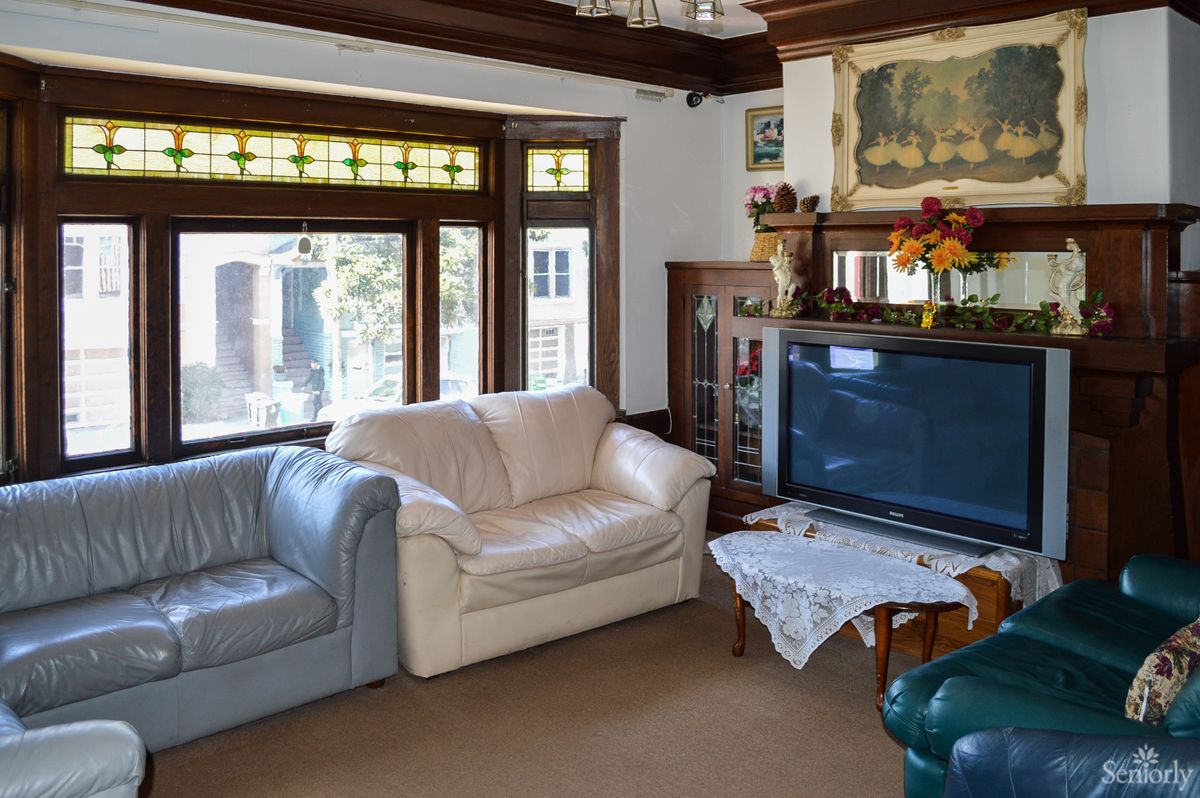 A cozy living room featuring sofas, a large television, and decorative elements with ample natural light from the windows.